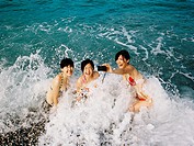 Three young woman splashed by ocean waves while trying to take a self portrait at Chi Shing Tan beach in Hualien, Taiwan