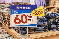 Sign indicates discounts on clothing in retail clothing bargain store.