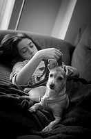 Teenage girl with her dog on the couch at home. Peniscola, Castellón, Valencia, Spain.