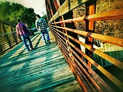 Two men walking casually into the distance across an iron bridge expressing a feeling of comfortable friendship