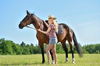 Young cowgirl with a polish arabian horse standing on a meadow.