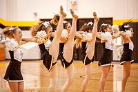 High school cheerleaders perform a high kick during a basketball game in Mission Viejo, CA.