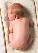 A naked newborn baby lies on a scale.