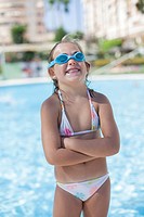 Pretty young girl in swimming pool laughing with Swim Goggles
