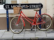 Red woman´s bicycle parked by St Michael´s Street road sign, Oxford, England, UK.