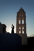 Silhouette of a woman taking photo near the Panagia Kimissis church situated at the cliff in Hora, Folegandros, Cyclades Islands, Greek Islands, Greec...