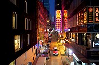 elevated view of taxi driving through neon lit restaurants and shops in Soho district, Hong Kong.