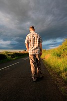 A man walking on the rural road in the golden sunlight.