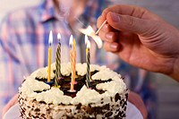 male hand lights the candles on the birthday cake.