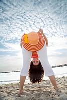 Young woman having fun with a straw hat on the beach
