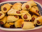 Pigs in a blanket is used to refer to sausages wrapped in biscuit dough, pancake, or croissant dough, and baked.