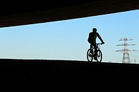 Back view of a biker cycling under the bridge. Anella verda del Prat de Llobregat, Barcelona province, Catalonia, Spain