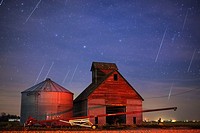 Geminid meteors streak across the sky behind a barn in western Iowa.