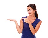 Hispanic lady in purple dress holding palm up and pointing to her right while looking at you smiling in white background - copyspace.