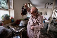 Zabolon Simantov, the last Afghan Jew, prepares cock for the dinner in his kitchen, Kabul, Afghanistan.
