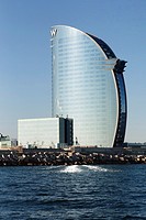 Barcelona - iconic ""Hotel W"" reflecting light in the form of the letter ""W"" on the Mediteranean Sea waves at dusk