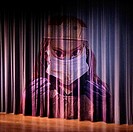 A stage curtain with the face of a scary doctor appearing on it.