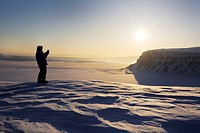 Expedition member looking over the frozen Tempelfjorden at sunset, Spitsbergen (Svalbard).