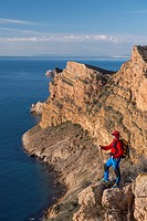 A men looks out over the Mediterranean sea from Sierra Helada natural park cliff, Benidorm, Alicante province, Spain.