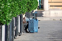 Woman sitting on bench with luggage in Rome, Italy