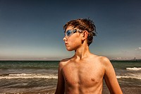 Boy wearing swimming googles at seaside.