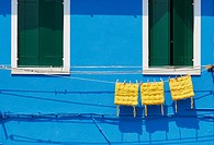Three yellow cushions hanging on line outside blue painted house, Burano, Venetian Lagoon, Veneto, Italy, Europe.