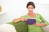 Caucasian young woman in a green shirt looking at the camera while holding a tablet - copy space.