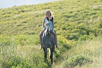 Barefoot girl riding a grey horse.