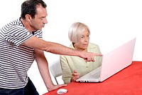 Technician helping an elderly woman use a laptop computer.
