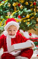 Surprised boy opens a Christmas gift, Christmas tree and gifts on background.