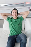 Portrait of a man lying on the sofa listening to music with headphones
