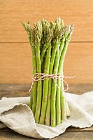 Bunch of fresh green asparagus on wooden table with linen cloth.