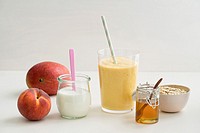 Healthy orange breakfast smoothie with yogurt, peach, mango, honey and oats in a glass.
