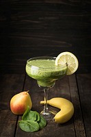 Healthy green smoothie made of pear, spinach and banana in a margarita glass.