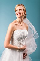 Beautiful bride wearing white wedding dress, blue background.