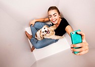 19 years old woman with cocker spaniel dog in white box taking selfie