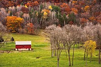 Red barn in valley with colorful autumn trees.