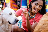 Hispanic woman trying on jewelry while playing with dogs at a street market in Puerto Vallarta, Mexico.