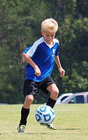 Young boy playing soccer wearing blue jersey.