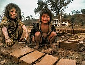 Brother and sister make mud bricks in wooden frame for parents house, Arun valley, Nepal.