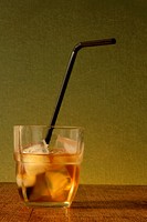Shot of whiskey on the rocks with black bending straw. Concept: under age drinking