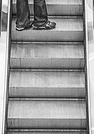 Escalator - black and white. Going up to the next floor - denims covering over legs. Cape Town, South Africa.