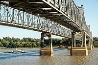 A tug boat pushes a barge beneath the bridge over the Mississippi at Natchez, TN. Tub.