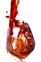 Drink, vigorously poured overflowing splashing from a wine glass, on a white background.