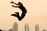 China, Shanghai, Young man performing parkour on roof of building