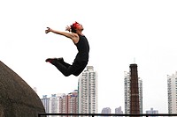 China, Shanghai, Young man performing parkour on roof of building