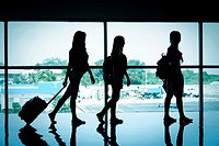 Silhouette of 3 female travelers at airport terminal.
