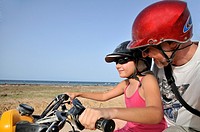 Girl (10) driving an ATV with her dad by seacoast, Djerba Island, Tunisia.