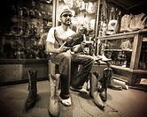 Hispanic man trying on stylish Mexican pointy boots in a store in Oaxaca Mexico.