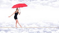 Barefoot woman, walking very focused on a rope with a red umbrella in hand, on the bottom white clouds in a blue sky.